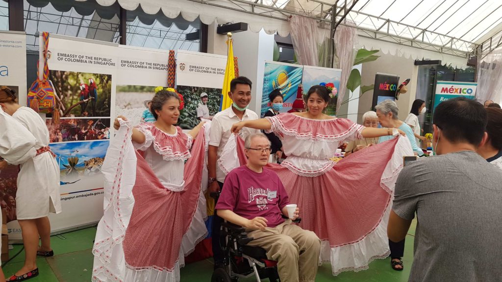Two women with their traditional clothes posing with two men, one of them in a wheelchair