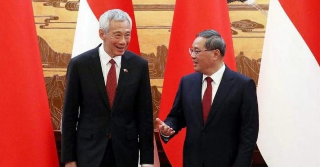 two men in a formal suit standing and talking in in front of China and Singapore flag